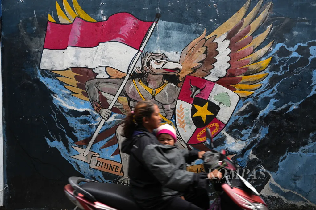 Motorcyclists pass a mural themed on diversity and peace in Semper Barat Subdistrict, Cilincing, North Jakarta, March 15, 2024.
